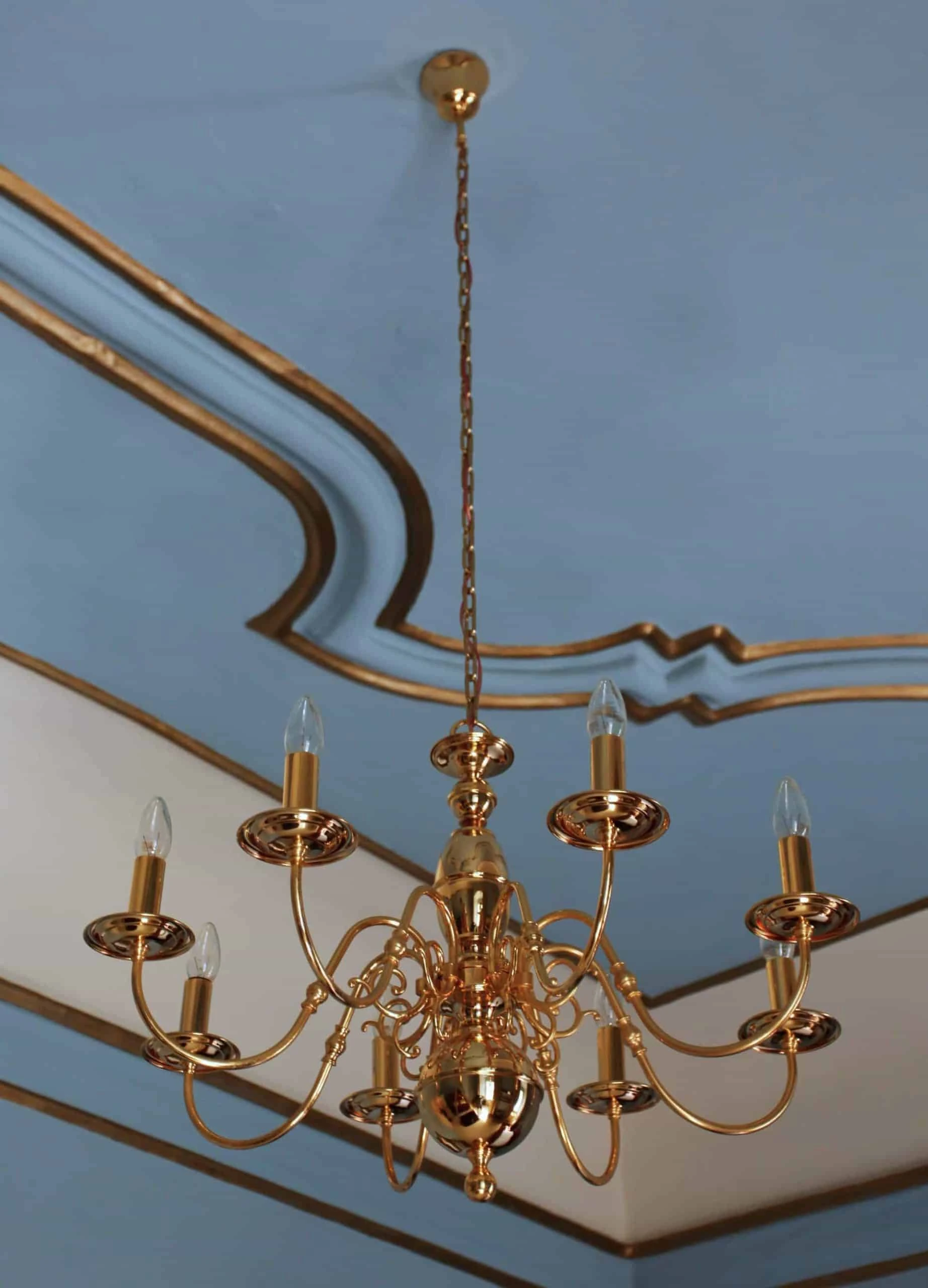 Osmiramenný lustr z leštěné mosazi.